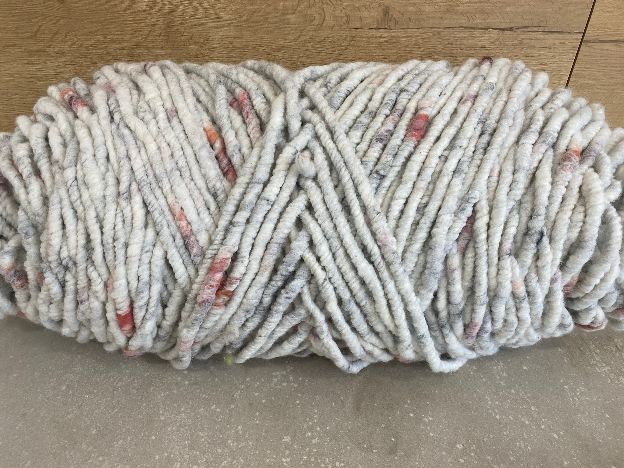 Weiß-grau meliertes Garn mit beerenrot, dick, ungefilzt