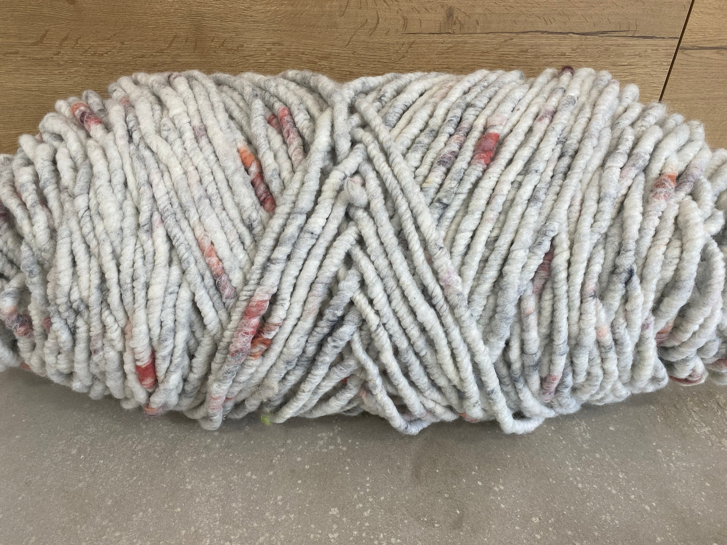 Weiß-grau meliertes Garn mit beerenrot, dick, ungefilzt